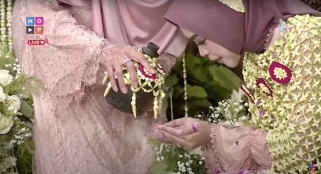 Setelah selesai, sisa air yang ada di dalam kendi dijadikan sebagai wudhu. Sang ibu sendiri yang menuangkan air dari kendi tersebut untuk dipergunakan oleh Ria Ricis. Foto: YouTube/MOP Channel