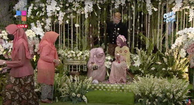 Selanjutnya dilakukan prosesi pemecahan kendi. Kendi yang dipergunakan untuk mengambil air siraman Ria Ricis itu kemudian dijatuhkan hingga pecah oleh orangtuanya. Foto: YouTube/MOP Channel