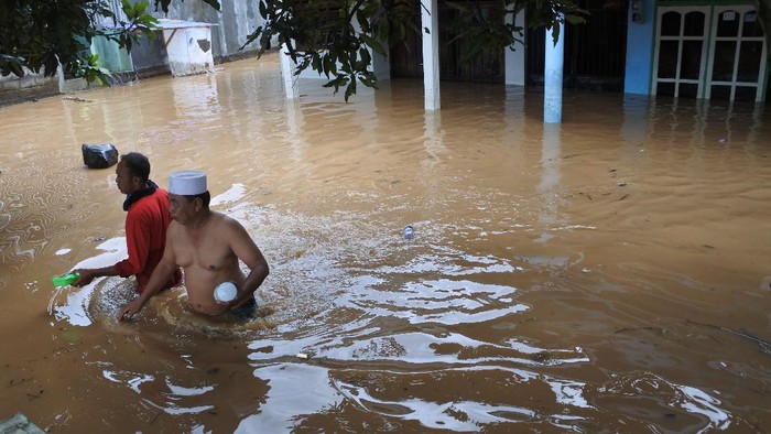 Warga melintasi banjir di Desa Pondok Joyo, Semboro, Jember, Jawa Timur, Kamis (11/11/2021). Menurut Badan Penanggulangan Bencana Daerah (BPBD) Jember sebanyak 1.294 rumah rumah warga terdampak banjir dan tanah longsor di tiga kecamatan di Jember yakni Semboro, Tanggul, dan Sumberbaru akibat hujan deras dan meluapnya air sungai sejak Rabu (10/11/2021). ANTARA FOTO/Seno/tom.