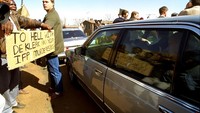 Pendemo berunjukrasa saat de Klerk melintas di dalam mobil, di Boipatong, Afsel (20/6/1992).  De Klerk dikenal kejam dengan kebijakan pemisahan ras di Afsel. Namun di penghujung karirnya, ia mencabut kebijakan itu dan mampu melakukan rekonsiliasi dengan kulit hitam. (AP Photo/Greg Mariovich/File)