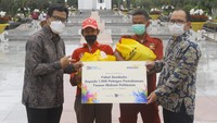VP Strategic Planning & Budgeting Bank Mandiri Satryo Widiarto (kiri) dan AVP CSR Dept Bank Mandiri Mashuri (kanan) menyerahkan paket sembako kepada petugas Taman Makam Pahlawan (TMP) Kalibata dalam menyambut Hari Pahlawan di Jakarta, Rabu (10/11).