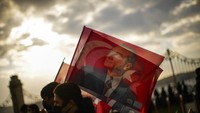 Bendera Turki dengan wajah pendiri republik, Mustafa Kemal Ataturk, dibawa oleh warga di Istanbul, (10/11). Warisan Ataturk sangat luas baik di dalam negeri maupun pengaruhnya ke luar negeri. Mustafa Kemal mengenalkan emansipasi untuk perempuan,  pengenalan pada kode hukum barat, pakaian, kalender, serta alfabet, mengganti seluruh huruf Arab dengan huruf Latin.  (AP Photo/Francisco Seco). 