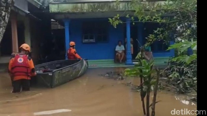 Petugas mengevakuasi warga menggunakan perahu