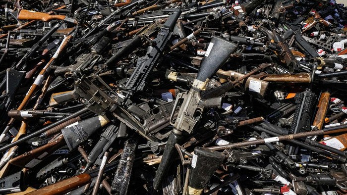 A Chilean Army officer shows weapons that were voluntarily turned over to police or seized, before melting them at a foundry in Santiago, Chile, Thursday, Nov. 11, 2021. More than 13,600 illegal weapons were destroyed, according to a national commission that regulates weapons. (AP Photo/Esteban Felix)
