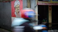 Salah seorang warga melintasi Gg H Sanan tempat mural Habib Rizieq.