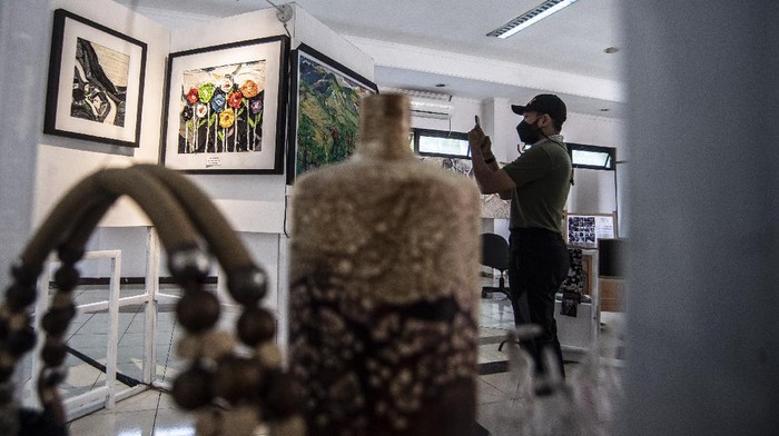Seorang pengunjung melihat salah satu lukisan berbahan limbah plastik di Aula Kelurahan Rawamangun, Jakarta, Jumat (12/11/2021). Lukisan berbahan baku limbah plastik yang merupakan hasil karya anggota LMK dan warga Rawamangun tersebut merupakan merupakan wujud kepedulian terhadap limbah plastik dalam mengelola sampah menjadi barang yang lebih berguna. ANTARA FOTO/Muhammad Adimaja/aww.