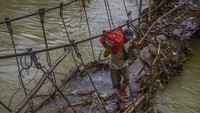 Seorang warga meniti jembatan gantung yang rusak pascabanjir bandang di Desa Hantakan, Kabupaten Hulu Sungai Tengah, Kalimantan Selatan, Jumat (12/11/2021).   