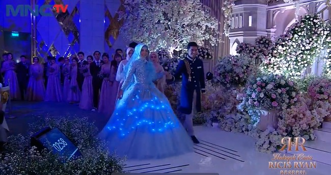 Dalam acara resepsi itu Ria Ricis dan Teuku Ryan tampak berdansa bak raja dan ratu semalam. Ricis tampil anggun dan cantik dalam balutan gaun berwarna biru. Gaunnya pun terlihat bisa menyala di tengah kegelapan. Foto: Instagram/@officialmnctv