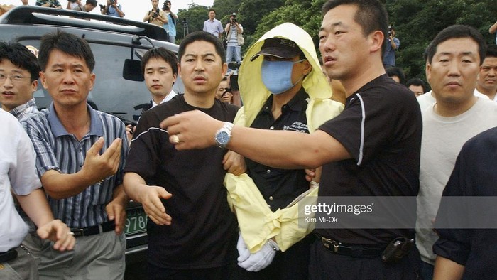 SEOUL, SOUTH KOREA - JULY 19:  Suspected serial killer, Yoo Young-Chul (C), is escorted by South Korean police during an inspection of suspected murder sites on July 19, 2004 in Seoul, South Korea. Police are expanding the investigation after securing testimony from Yoo, a 34-year-old suspected of killing at least 19 people, that he had committed more murders in Pusan and Inchon.  (Photo by Kim Mi-Ok/Getty Images)