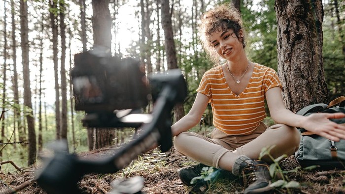 Influencer vlogging while spending time alone in forest.