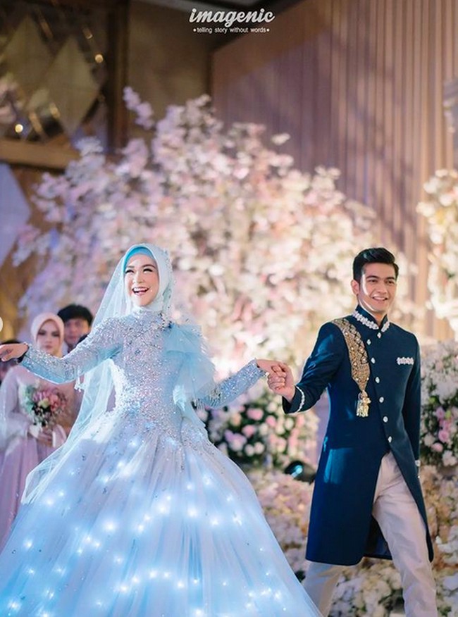Gaun pengantin karya Lisa Ju dari Bandung itu hadir dalam siluet ball-gown yang megah. Istimewanya, bagian rok gaun tersebut mengeluarkan cahaya. (Foto: Instagram/@riaricis1795/@imagenic)
