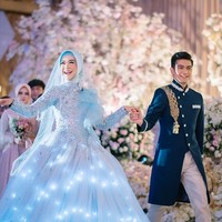 Gaun pengantin karya Lisa Ju dari Bandung itu hadir dalam siluet ball-gown yang megah. Istimewanya, bagian rok gaun tersebut mengeluarkan cahaya. (Foto: Instagram/@riaricis1795/@imagenic)