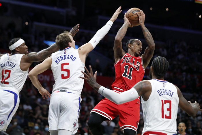 Chicago Bulls forward DeMar DeRozan (11) passes the ball away from pressure by Los Angeles Clippers guard Eric Bledsoe, left, guard Luke Kennard (5) and guard Paul George (13) during the second half of an NBA basketball game Sunday, Nov. 14, 2021, in Los Angeles. (AP Photo/Alex Gallardo)