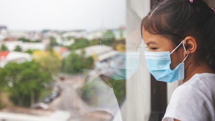 Hari Anak Sedunia: Ini Sejarah dan Serba-serbinya Asian child girl wearing protection mask looking outside through the window and stay at home quarantine from the coronavirus Covid-19 and air pollution pm2.5.