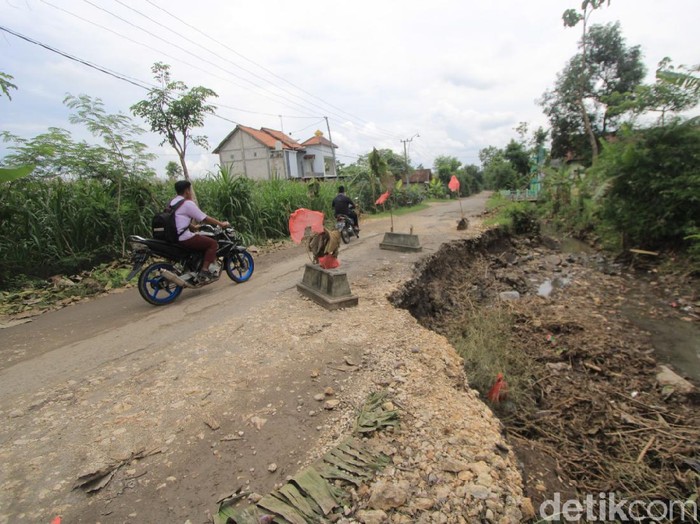 Ada jalan yang ambrol di Desa Ringinputih, Kecamatan Sampung, Ponorogo. Warga menaruh empat batu nisan atau yang biasa disebut kijing di jalan tersebut.