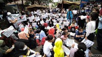 Massa demo membawa poster berisikan tuntutan. 