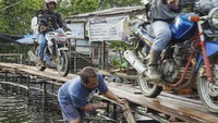 Warga memperbaiki jembatan kayu darurat di atas Jalan Trans Kalimantan Sintang-Putussibau yang terendam banjir di Akcaya, Kabupaten Sintang, Kalimantan Barat.