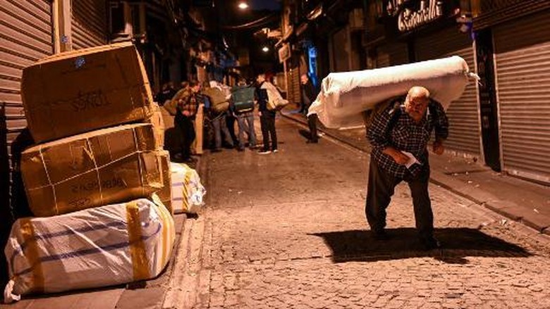 A porter carries belongings on a street early morning, on October 28, 2021 near Grand bazaar in Istanbul. - Just blocks from Istanbuls Grand Bazaar, porter Bayram Yildiz waits his turn in a dark alley to heave a huge bale on his back nearly double his bodyweight. A few others linger beside him, picking up textiles from a lorry and lugging them to local shops before sunrise, their heads bowed and their knees bent.