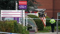 Seorang petugas polisi berjalan melewati mobil pemadam kebakaran di rumah sakit Wanita Liverpool. Detektif dari Polisi Kontra Terorisme North West mengatakan tiga pria di daerah Kensington di kota itu ditangkap berdasarkan Undang-Undang Terorisme.