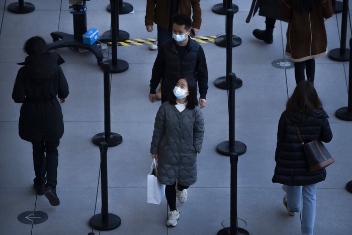 Orang-orang yang memakai masker untuk melindungi diri dari COVID-19 mengantre untuk masuk ke toko di pusat perbelanjaan luar ruangan di Beijing, Sabtu, 13 November 2021.