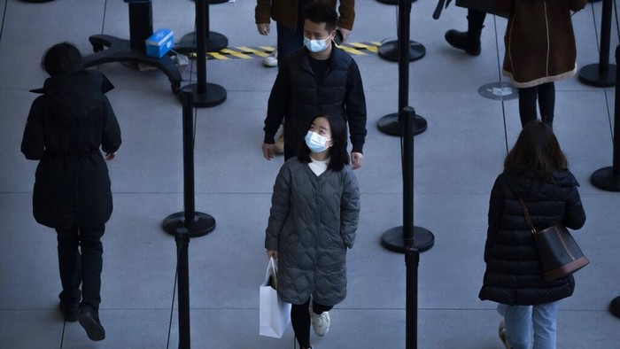 Orang-orang yang memakai masker untuk melindungi diri dari COVID-19 mengantre untuk masuk ke toko di pusat perbelanjaan luar ruangan di Beijing, Sabtu, 13 November 2021.