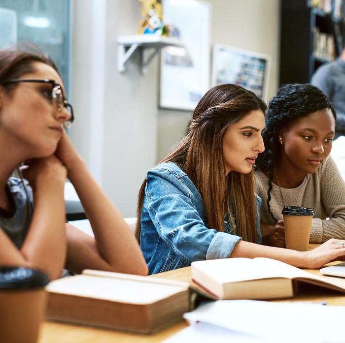 Shot of two young women using a laptop together in a college library