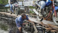 Warga memperbaiki jembatan kayu darurat di atas Jalan Trans Kalimantan Sintang-Putussibau yang terendam banjir di Akcaya, Kabupaten Sintang, Kalimantan Barat, Senin (15/11/2021). ANTARA FOTO/Abraham Mudito  