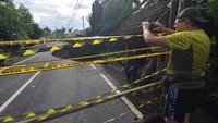 Wisatawan memotret jalan raya ambles di Desa Pejeng, Gianyar, Bali. 