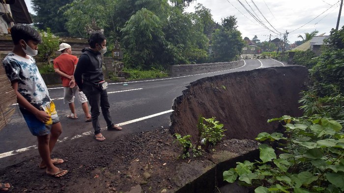 JALAN RAYA AMBLES DI GIANYAR Warga melintas di dekat jalan ambles di Desa Pejeng, Gianyar, Bali, Selasa (16/11/2021). Amblesnya jalan raya yang merupakan jalur akses menuju Kota Gianyar itu disebabkan kelabilan tanah setelah terjadi hujan deras pada Senin (15/11/2021) dan tidak ada korban dalam peristiwa itu. ANTARA FOTO/Nyoman Hendra Wibowo/rwa.