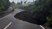 Warga melintas di dekat jalan ambles di Desa Pejeng, Gianyar, Bali, Selasa (16/11/2021).