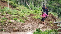Beberapa warga tampak mencoba lewat dengan berjalan kaki di atas material yang menutup jalan.