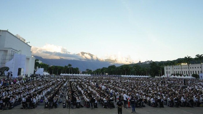 Meriahnya Orkesta Terbesar di Dunia Nicolas Maduro Guerra, center, son of Venezuelan President Nicolas Maduro, takes part in an attempt to try and break a Guinness World Record in Caracas, Venezuela, Saturday, Nov. 13, 2021. The musicians, all connected with the country network of youth orchestras, played at a military base under the watchful eyes of hundreds of independent supervisors tasked with verifying that more than 8,097 instruments are played at the same time. (AP Photo/Ariana Cubillos)