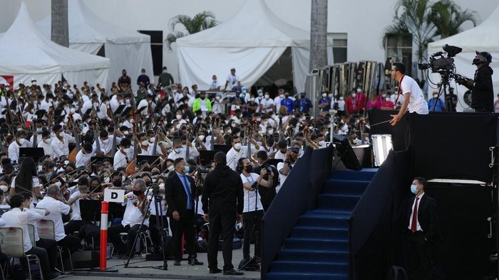 Meriahnya Orkesta Terbesar di Dunia Nicolas Maduro Guerra, center, son of Venezuelan President Nicolas Maduro, takes part in an attempt to try and break a Guinness World Record in Caracas, Venezuela, Saturday, Nov. 13, 2021. The musicians, all connected with the country network of youth orchestras, played at a military base under the watchful eyes of hundreds of independent supervisors tasked with verifying that more than 8,097 instruments are played at the same time. (AP Photo/Ariana Cubillos)