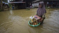 Warga membawa bahan makanan melewati banjir di Desa Jaranih, Kabupaten Hulu Sungai Tengah, Kalimantan Selatan.