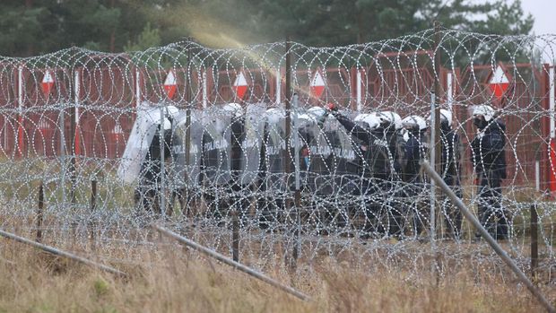EUROPE-MIGRANTS/BELARUS-POLAND Polish law enforcement officers stand guard behind a fence, as migrants attempt to cross the Belarusian-Polish border at Bruzgi - Kuznica checkpoint in the Grodno region, Belarus November 16, 2021. Leonid Scheglov/BelTA/Handout via REUTERS ATTENTION EDITORS - THIS IMAGE HAS BEEN SUPPLIED BY A THIRD PARTY. NO RESALES. NO ARCHIVES. MANDATORY CREDIT.
