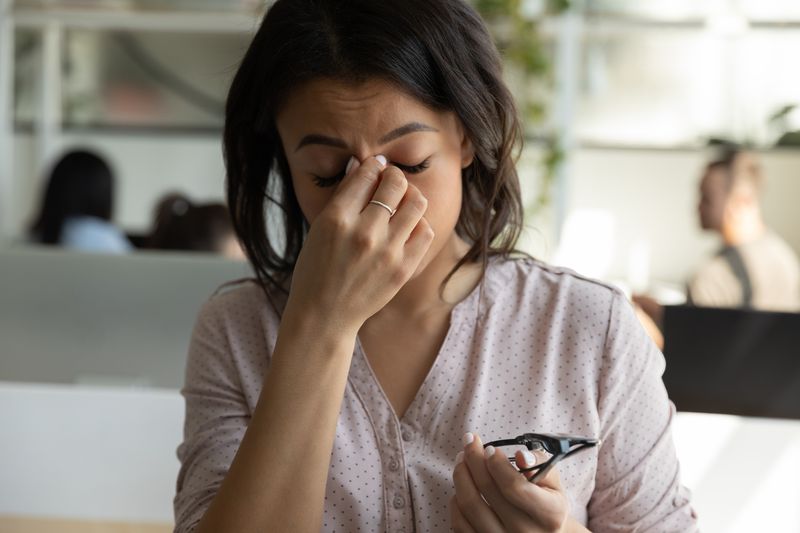 Tired mixed race Black business woman, office employee touching, rubbing nose bridge with closed irritable eyes, bad strain blurry vision, eyesight problems, headache, feeling stress, fatigue