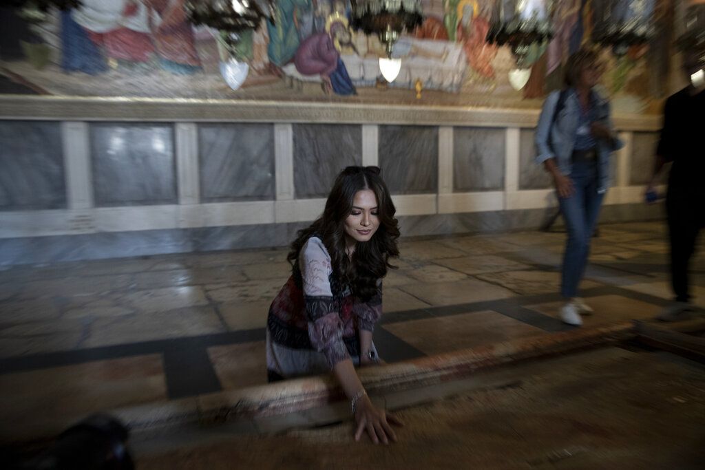 Andrea Meza, the reigning Miss Universe from Mexico, places her hand on the Stone of Unction in the Church of the Holy Sepulchre as she tours the Old City of Jerusalem, Wednesday, Nov. 17, 2021, ahead of the 70th Miss Universe pageant being staged in the southern Israeli resort city of Eilat next month. The stone slab is traditionally believed to be the stone where Jesus' body was prepared for burial. She said Wednesday that the long-running beauty pageant shouldn't be politicized, even as its next edition is being held in Israel and contestants have faced pressure to drop out in solidarity with the Palestinians. (AP Photo/Maya Alleruzzo)