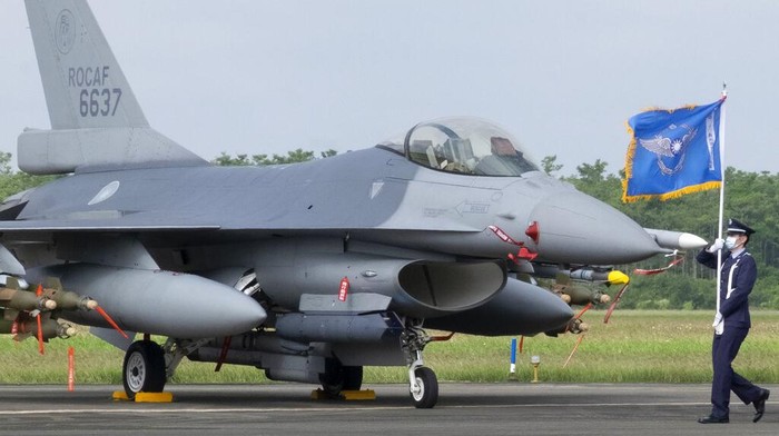 Tangkal Ancaman China, Taiwan Resmikan Jet Tempur Canggih F-16V A Taiwanese Air Force flag bearer passes by one of the newly commissioned upgraded F-16V fighter jets at Air Force base in Chiayi in southwestern Taiwan Thursday, Nov. 18, 2021. Taiwan has deployed the most advanced version of the F-16 fighter jet in its Air Force, as the island steps up its defense capabilities in the face of continuing threats from China. (AP Photo/Johnson Lai)