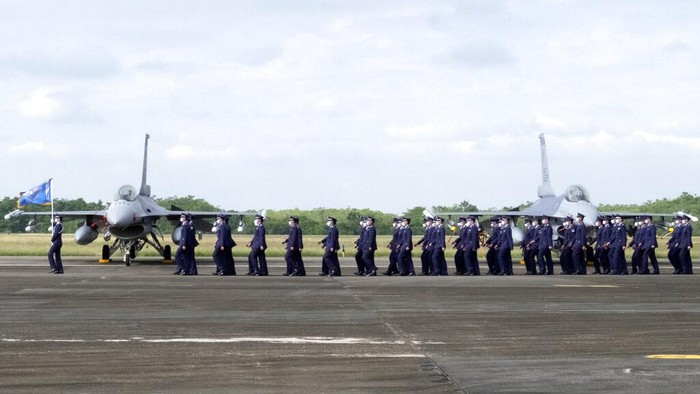 A Taiwanese Air Force flag bearer passes by one of the newly commissioned upgraded F-16V fighter jets at Air Force base in Chiayi in southwestern Taiwan Thursday, Nov. 18, 2021. Taiwan has deployed the most advanced version of the F-16 fighter jet in its Air Force, as the island steps up its defense capabilities in the face of continuing threats from China. (AP Photo/Johnson Lai)