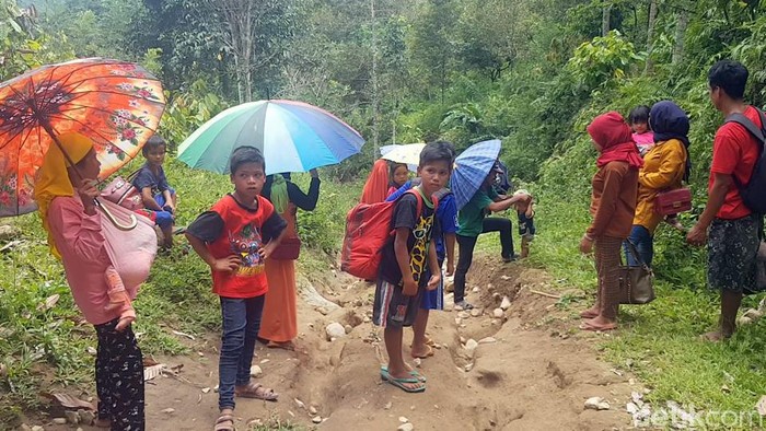 Warga pergi meninggalkan desa untuk mencari makan dengan melewati akses jalan yang sulit akibat longsor