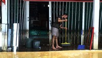 Seseorang tengah membersihkan sisa genangan air dari tokonya yang sebelumnya terendam banjir besar di Jalan Lintas Melawi, Sintang, Kalimantan Barat, Jumat (19/11/2021).