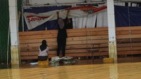 Dua karyawan berada di depan toko ritel yang rusak berusaha memperbaikinya dan membersihkan sisa banjir.