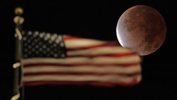 Gerhana Bulan sebagian di belakang bendera Amerika Serikat. Foto: Associated Press