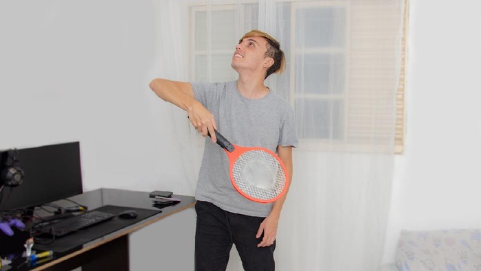 portrait young man holding electric racquet.