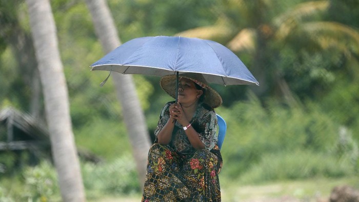 Menonton Latihan Bebas WSBK dari Perbukitan A woman braves the heat with an umbrella to watch the free practice1 Superbike World Championship outside Mandalika International Circuit in Mandalika, Lombok Island, Indonesia, Friday, Nov. 19, 2021. (AP Photo/Achmad Ibrahim)