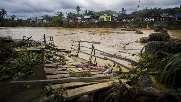 Sungai Hantakan di kawasan Kalimantan Selatan meluap. Akibatnya, sebuah jembatan darurat terbawa arus dan satu sekolah dasar dipenuhi lumpur. Ini potretnya.