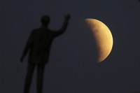 I this Tuesday, July 16, 2019 photo, men stand below street lights as the moon rises during a partial lunar eclipse in Buenos Aires, Argentina. (AP Photo/Natacha Pisarenko)
