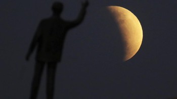 Patung mantan Presiden Brasil Juscelino Kubitschek, pendiri Brasilia, seakan menyambut gerhana Bulan parsial di langit Brasilia, Brasil, Selasa, 16 Juli 2019. Gerhana bulan sebagian yang terlihat di seluruh Brasil terjadi pada hari yang sama dengan tanggal perayaan 50 ulang tahun pendaratan manusia di Bulan. Foto: AP/Natacha Pisarenko 