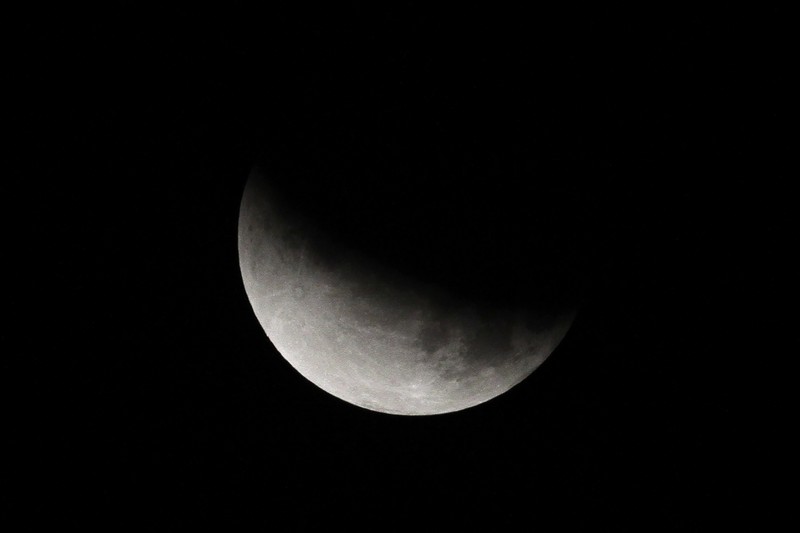 I this Tuesday, July 16, 2019 photo, men stand below street lights as the moon rises during a partial lunar eclipse in Buenos Aires, Argentina. (AP Photo/Natacha Pisarenko)