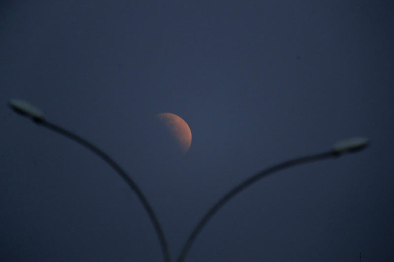 I this Tuesday, July 16, 2019 photo, men stand below street lights as the moon rises during a partial lunar eclipse in Buenos Aires, Argentina. (AP Photo/Natacha Pisarenko)